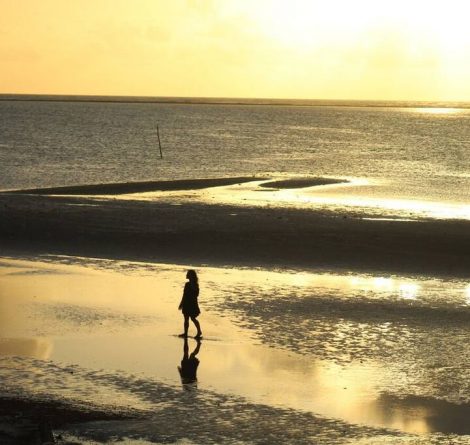 pessoa passeando na areia da praia, buscando o que fazer em Japaratinga